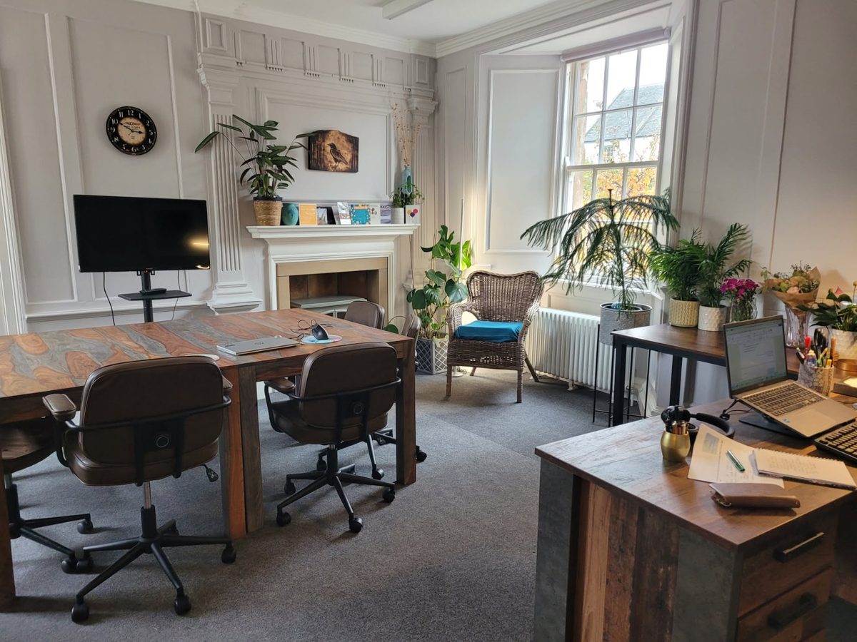 The training room at Eildon IT Training in Haddington House, with a shared table, a screen, a fireplace and plants