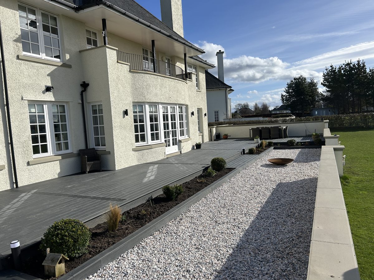 Grey composite decking, a gravel walkway and new planting beds installed by Mitchell Landscaping at a large East Lothian home