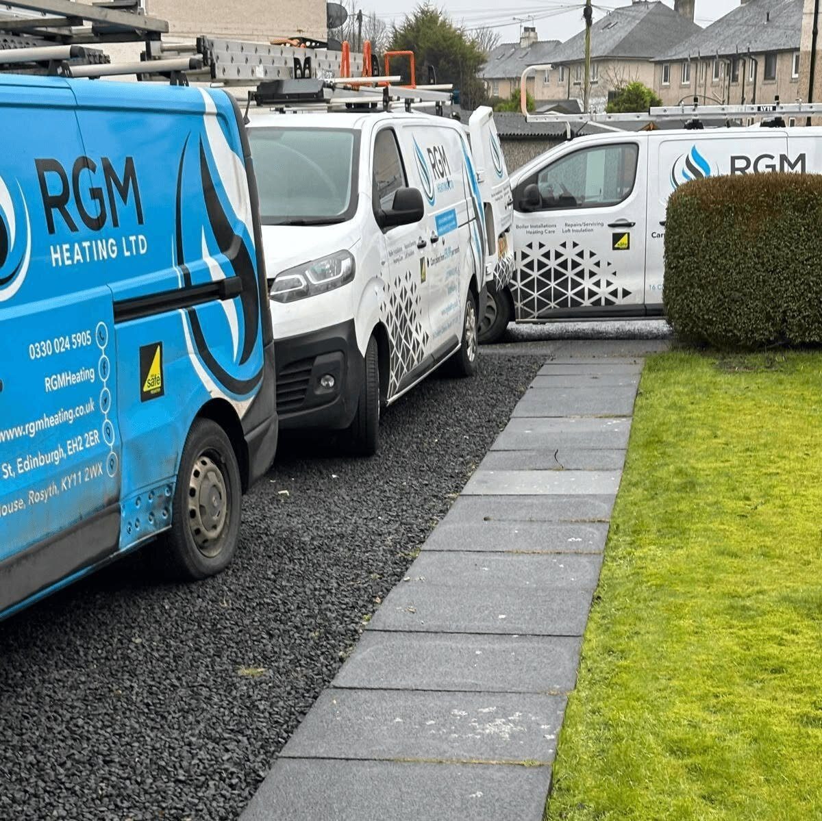 Three branded RGM Heating Ltd vans parked on a driveway in Fife
